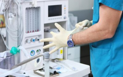 The doctor puts on gloves against the background of a ventilator. Unrecognizable photo. Copy of the space. The doctor puts on gloves against the background of a ventilator. Unrecognizable photo. Copy space.