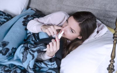 Young woman using nasal spray.Sick woman in bed having sinusitis ache and stuffy nose Young woman using nasal spray.Sick woman in bed having sinusitis ache and stuffy nose