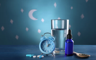 Alarm clock and different remedies for insomnia treatment near glass of water on table against blue wall decorated with stars and crescent Alarm clock and different remedies for insomnia treatment near glass of water on table against blue wall decorated with stars and crescent